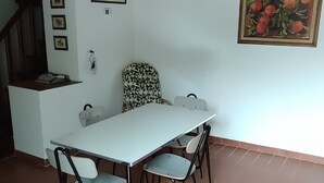 Un comedor con una mesa y sillas blancas, ventilador de techo y piso de baldosas.