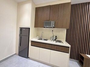 Eine kleine Küche mit Kühlschrank, Mikrowelle, Spüle und Holzschränken.