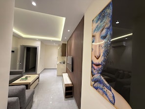 Ein modernes Interieur mit einer Couch, einem Couchtisch, einem Gemälde und einer Küchenzeile.