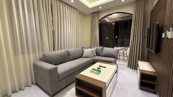 A modern living room with a grey sofa, a wooden coffee table, and a TV mounted on the wall.