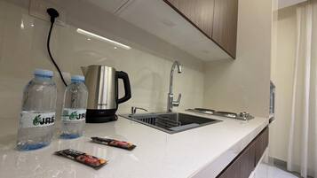A modern kitchen with a stainless steel sink, a kettle, and bottled water.