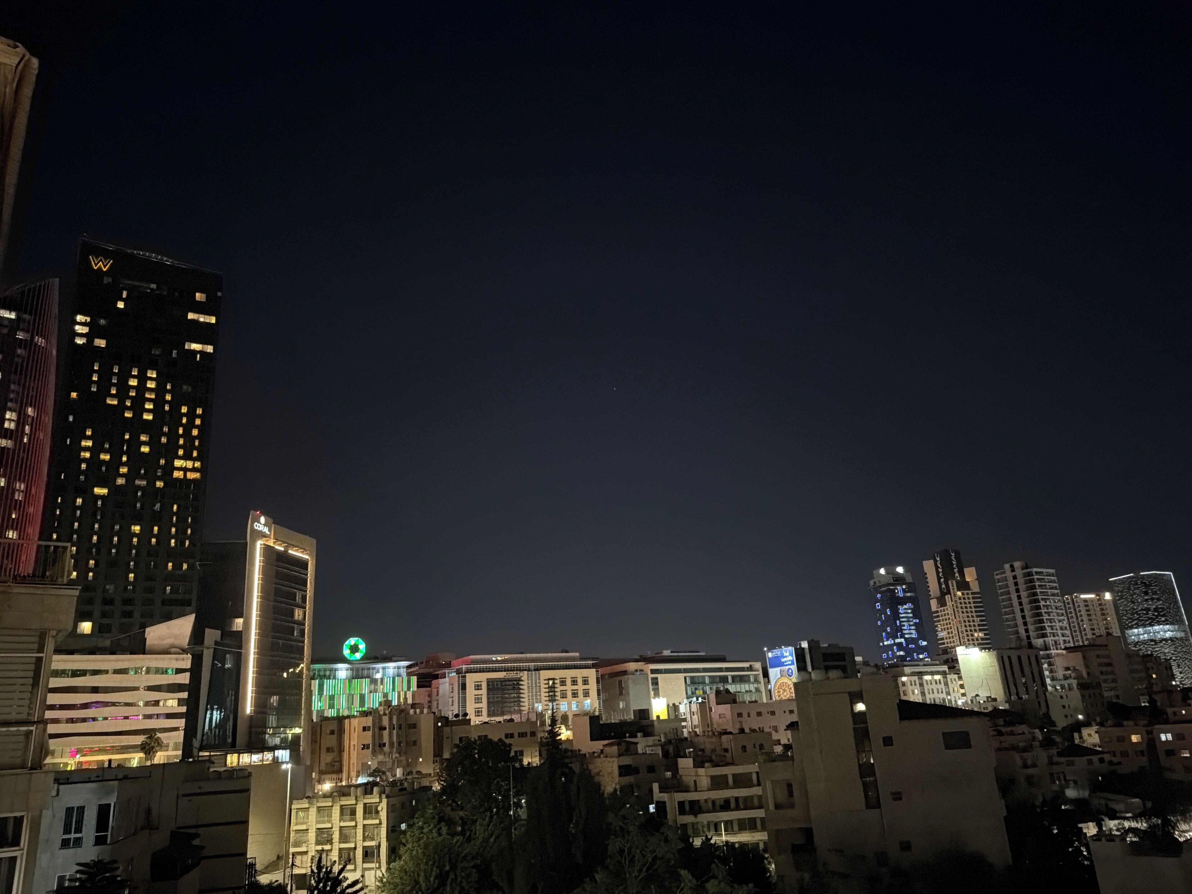 A nighttime cityscape with illuminated buildings, including a hotel with a prominent 'W' sign.