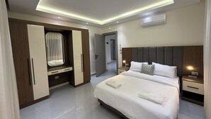 A modern bedroom with a large bed, bedside tables, a wardrobe, and a ceiling light fixture. - 301 JRE 2Bedr rooftop with beautiful view (Amman)