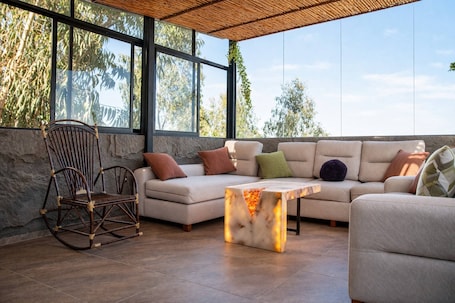 An outdoor seating area with a sofa, a rocking chair, and a table with a built-in light.. La Casita de Luna Bolivia
