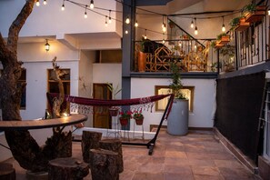 A cozy courtyard with a hammock, rustic wooden furniture, and string lights. - La Casita de Luna Bolivia (Sucre)
