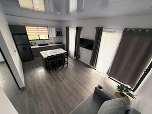 A modern kitchen with a dining area, a sofa, and a window with curtains. - View 4 Villas Vista Verde (Coronado)