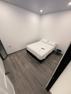 A small, modern bedroom with a bed, a small round table, and a mirror. - View 4 Villas Vista Verde (Coronado)