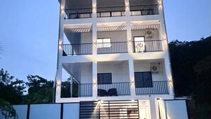 Ein mehrstöckiges Gebäude mit Balkonen, einem verschlossenen Eingang und einem flachen Dach.