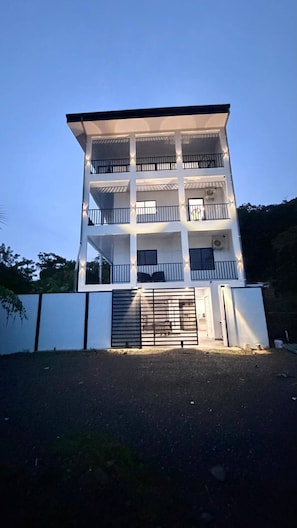 A multi-story building with balconies, a gated entrance, and a flat roof.