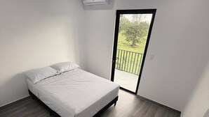 Ein Schlafzimmer mit Bett, einer Schiebetür zum Balkon und einer Klimaanlage.