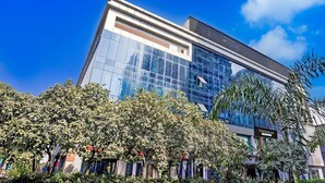 Un edificio moderno con fachada de vidrio, rodeado de exuberante vegetación.