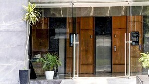 Una entrada moderna de edificio con puertas de vidrio, una planta en maceta y un cartel en la pared.