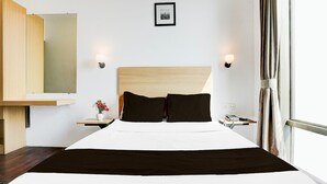Habitación de hotel con cama, mesitas de noche, espejo, un cuadro en la pared y ventana con cortinas.