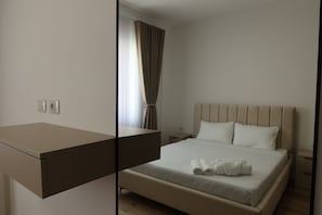 A hotel room with a bed, a bedside table, a nightstand, and a mirror. - PineaMare Apartaments Golem, Durres (Golem)