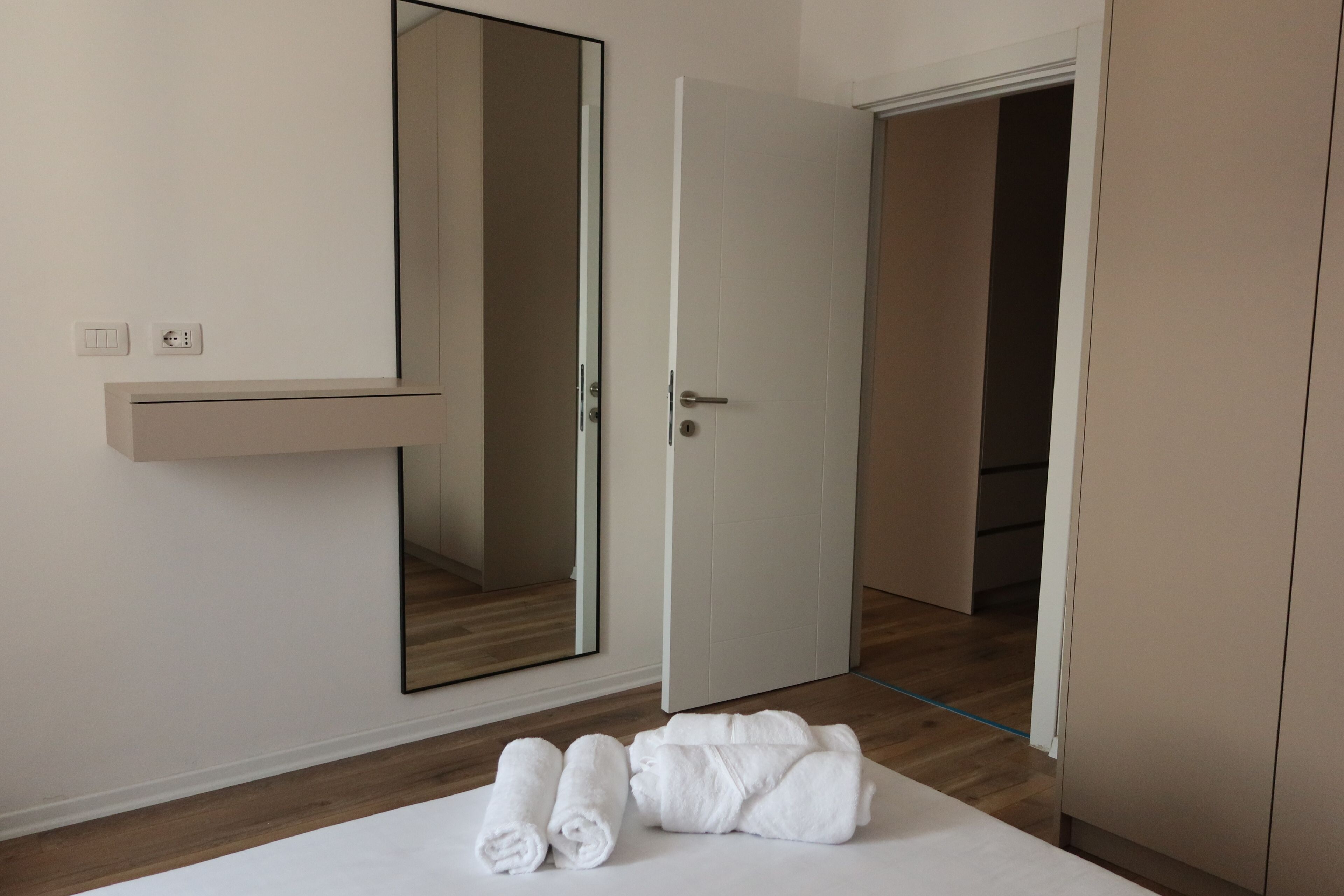 Ein Hotelzimmer mit einem Bett, einem Spiegel, einer Tür und Holzboden.