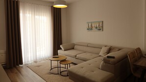 Ein Wohnzimmer mit einer Couch, zwei kleinen Tischen, einem Gemälde und einer Deckenleuchte.