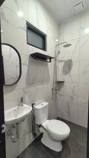 A bathroom with a toilet, sink, and shower. - Puri 7 Guesthouse (Palembang)