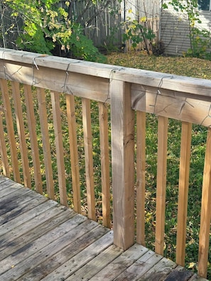 A wooden deck with a railing, surrounded by grass and a wooden fence. - Modern 3-bedroom Retreat Near Moncton Hospital and Downtown (Moncton)