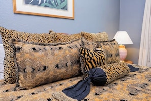 Ein Bett mit Leopardenmuster-Kissen und einer gemusterten Tagesdecke.