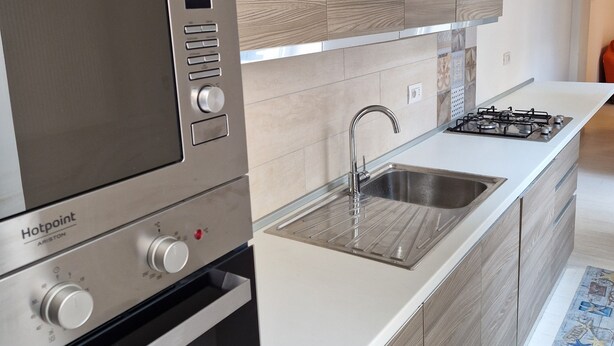 Une cuisine moderne équipée d’un four encastré, d’une plaque de cuisson et d’un évier.