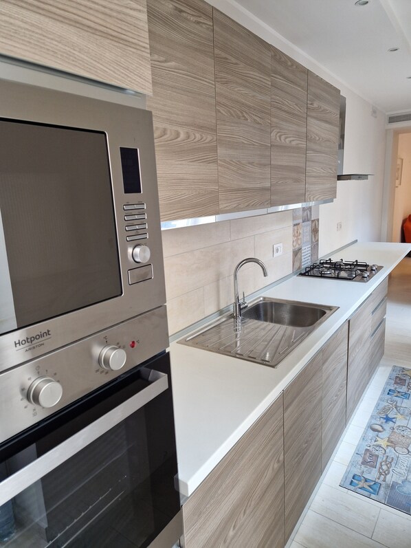 A modern kitchen with a built-in oven, a stovetop, and a sink. - Apartments Villa Fulgida Ground Floor (Cattolica)