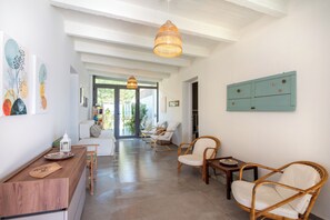 A spacious living area with a wooden coffee table, wicker chairs, and a hanging light fixture. - Villa Isabelle on the beach (Iria)