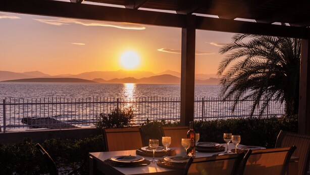 Ein Tisch für zwei Personen mit Blick auf den Sonnenuntergang über dem Meer.