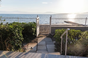 A pathway leading to a beach with a fence, a gate, and a view of the sea and distant mountains. - Villa Isabelle on the beach (Iria)