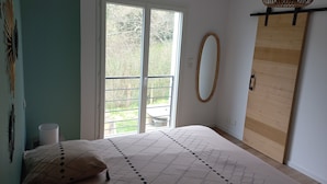 Ein Schlafzimmer mit einem Bett, einem Fenster, einem Spiegel und einem Holzschrank.
