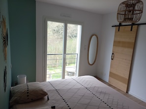 Ein Schlafzimmer mit einem Bett, einem Fenster, einem Spiegel und einem Holzschrank.