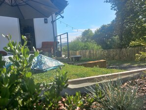 Ein Garten mit einer Terrassenfläche, einem Holzzaun und Blick auf die umliegende Landschaft.