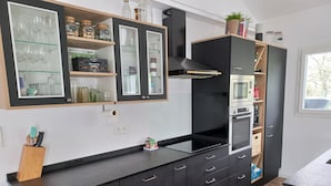 Eine moderne Küche mit schwarzen Schränken, einem eingebauten Backofen und einem Fenster für natürliches Licht.
