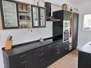 Eine moderne Küche mit schwarzen Schränken, einem eingebauten Backofen und einem Fenster für natürliches Licht.