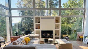 Ein modernes Wohnzimmer mit großem Fenster, Kamin und einer Couch.