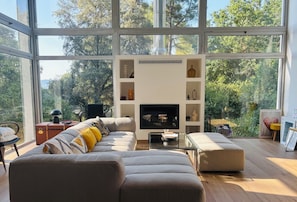 Ein modernes Wohnzimmer mit großem Fenster, Kamin und einer Couch.