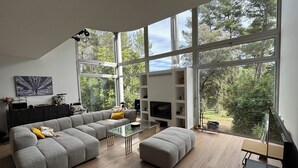 Ein modernes Wohnzimmer mit großem Fenster, einer Couch, einem Glastisch und einem Fernseher.