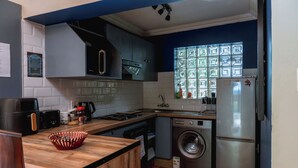 Eine kleine Küche mit Waschmaschine, Kühlschrank und Mikrowelle.