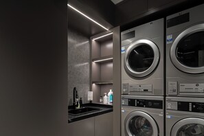 Uma lavanderia moderna com várias máquinas de lavar, uma pia e dispensadores de sabonete líquido.