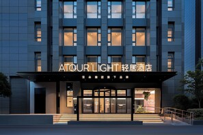 Ingresso moderno di un hotel con un cartello che riporta 'ATOUR LIGHT'.