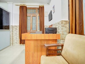 A living room with a wooden coffee table, a sofa, a television, and a fireplace. - Collection O Aishbagh Railway Junction (Lucknow)