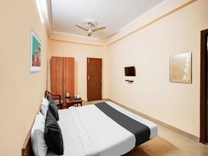 A hotel room with a bed, a desk, a chair, a ceiling fan, a TV, and a door. - Collection O Aishbagh Railway Junction (Lucknow)