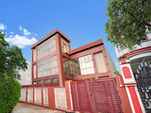 A modern building with a red and white facade, large windows, and a gated entrance. - Collection O Aishbagh Railway Junction (Lucknow)