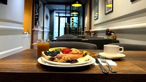 En matplats med ett bord dukat för frukost, inklusive en tallrik med mat, ett glas juice och en kopp.