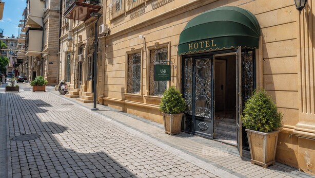 En historisk byggnad med en skylt som visar att det är ett hotell, stora, välvda fönster och en kullerstensgata.