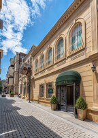 Un edificio histórico con un letrero que dice 'HOTEL', ventanas arqueadas grandes y una calle adoquinada.
