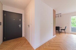 Ein modernes Interieur mit einer dunklen Tür, einem Essbereich mit Tisch und Stühlen sowie einem großen Fenster.