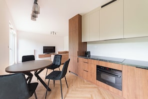 A modern kitchen with wooden cabinets, a black countertop, and a built-in oven.