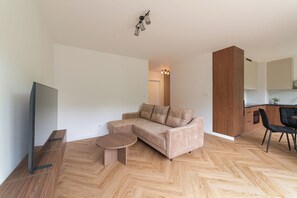 A modern living room with a sofa, a coffee table, a flat-screen TV, and wooden flooring.