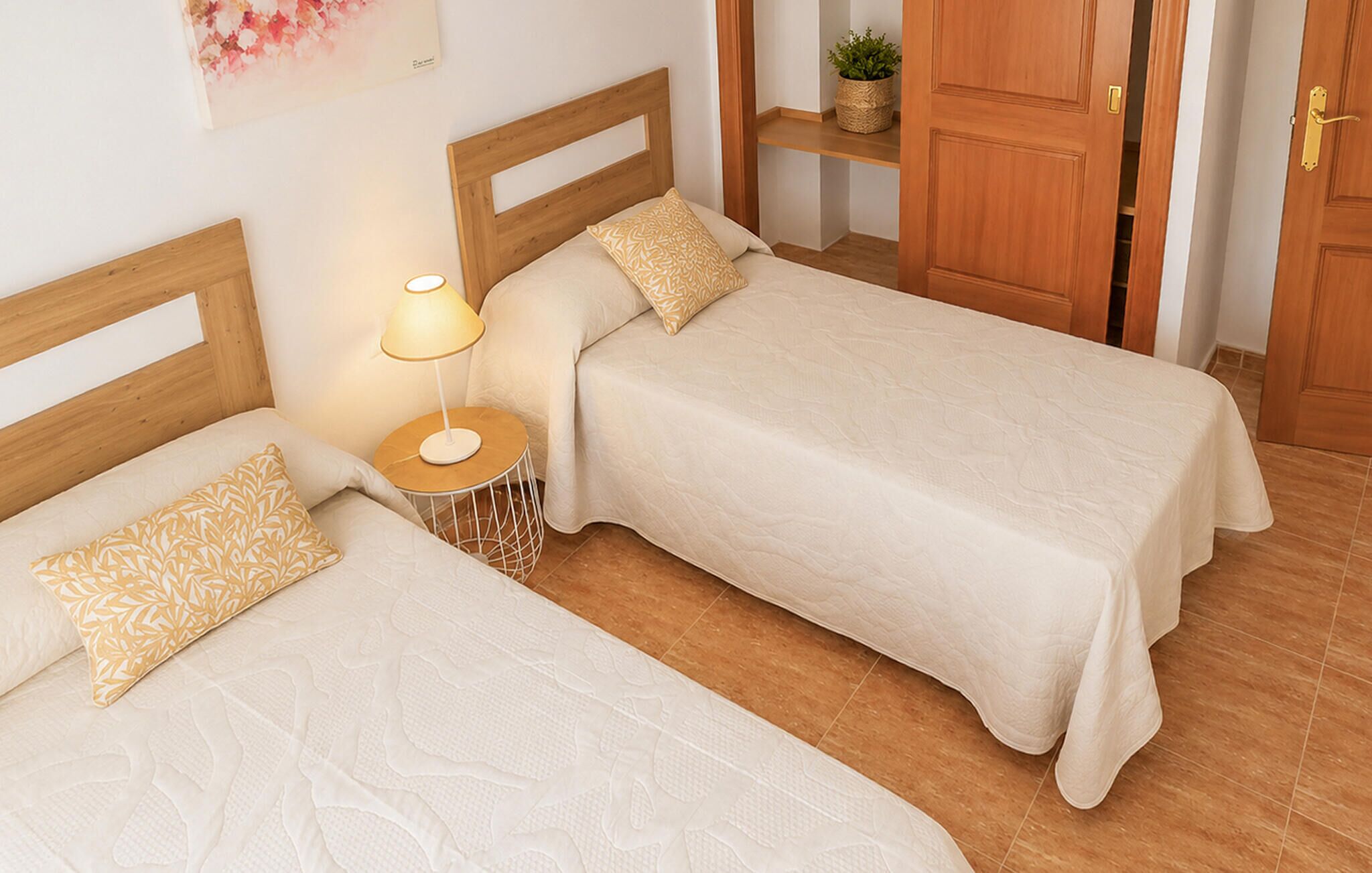 Two single beds with wooden headboards, a bedside table with a lamp, and a wooden door.