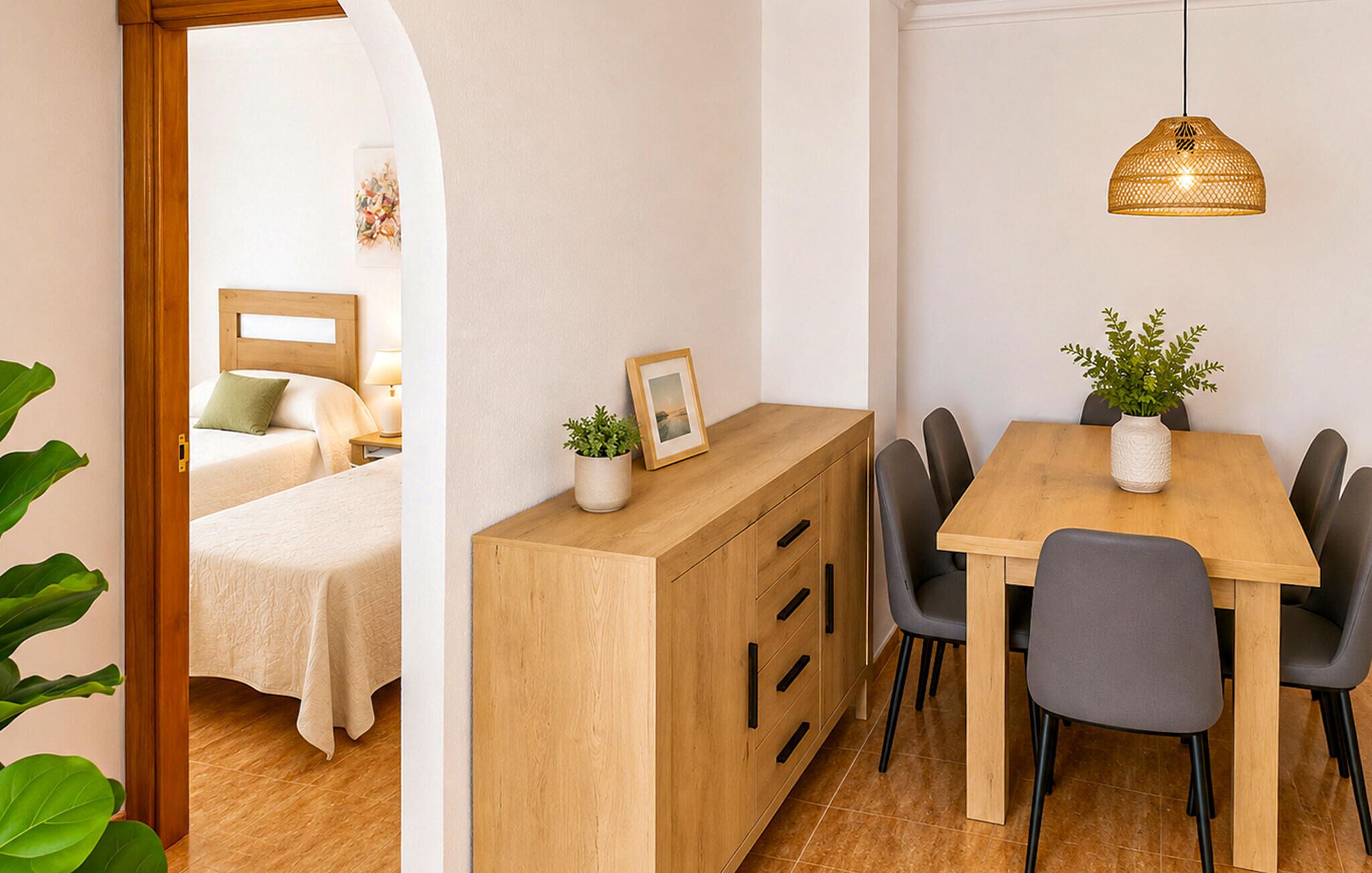 A hotel room with a bed, bedside table, and a view through an archway.